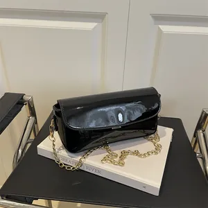 Chic black oil wax leather baguette bag with gold chain strap on minimalist book