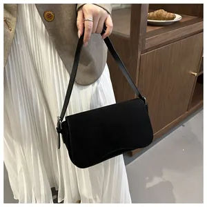 Detail of matte black underarm bag with adjustable leather strap and silver buckle
