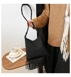 Détail d'un sac sous le bras noir avec franges longues et bandoulière cylindrique