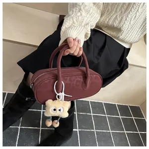 Close-up of burgundy baguette bag with leopard print and plush monster charm detail