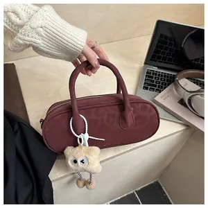 Detail of dark red leopard print barrel bag featuring a plush monster charm on its handle