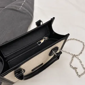 Close-up of the smooth silver zipper detail on the black and white tote bag