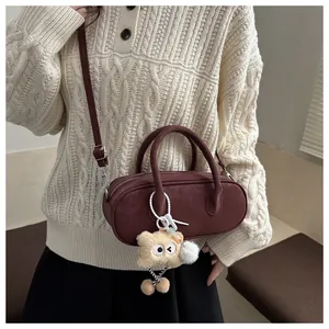 Detail view of burgundy minimalist handbag with monster plush charm and crossbody strap