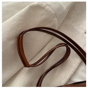 Detail of comfortable brown leather shoulder strap with protective padding on corduroy