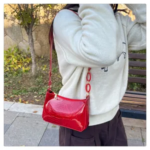 Détail d'un sac à bandoulière rouge en similicuir avec texture croco et chaîne acrylique