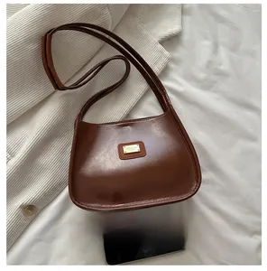 Detail view of a vintage dark brown semi-circular underarm bag on soft white fabric