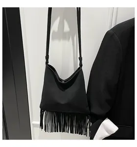 Détail du sac bandoulière noir montrant le design des longues franges et la texture mate