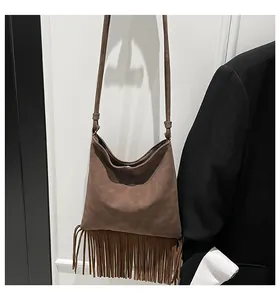 Détail du sac bandoulière en daim marron foncé avec de longues franges et nœud stylé