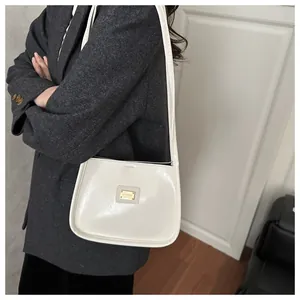 Detail of white leather shoulder bag featuring a sleek saddle shape and gold logo plate