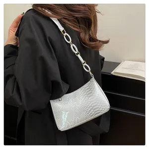 Détail du sac à bandoulière blanc gaufré serpent avec chaîne en résine porté par le mannequin