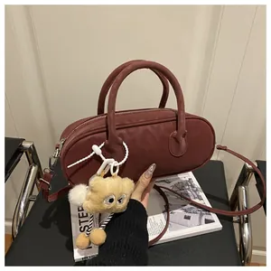 Close-up of a burgundy leather Boston bag featuring a playful yellow plush eye charm