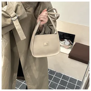 Chic cream leather handbag with dual handles and long strap in a modern office setting