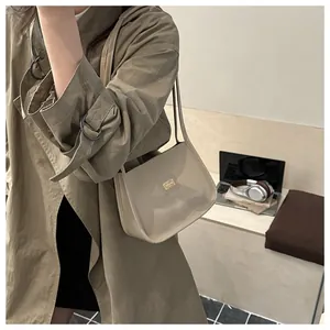 Detail of a chic beige leather underarm bag with a metal logo plate on an office desk