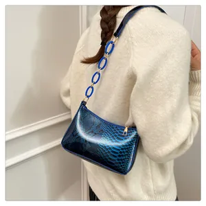 Vue détaillée du sac d'épaule bleu à motif serpent avec chaîne acrylique sur un modèle