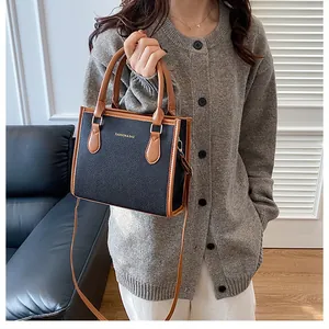 Detalle de cuero negro con textura de lichi y correas marrones en un bolso bandolera casual