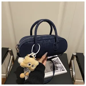 Close-up of a dark blue cylinder bag with leopard pattern and a plush bear charm