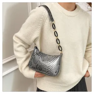 Détail de la texture serpent argentée et de la chaîne en résine noire sur le sac à main
