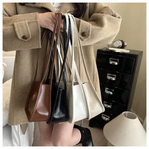 Detailed view of four minimalist faux leather underarm bags in brown, black, and white colors