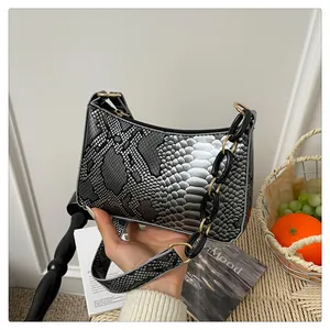 Détail du sac sous le bras motif serpent argenté avec chaîne dorée en décor intérieur