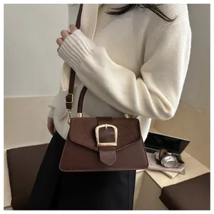 Detail of coffee brown crossbody bag featuring suede patchwork and gold square buckle