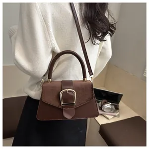 Detail view of brown patchwork leather crossbody bag with elegant gold buckle and shoulder strap