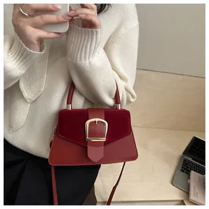 Detail of red velvet patchwork handbag with a large gold square buckle and leather strap