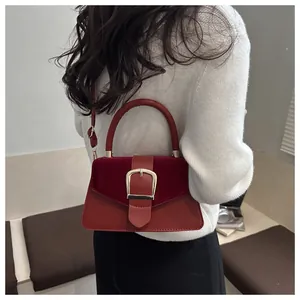 Detail of red leather and velvet handbag featuring a large gold square buckle and strap