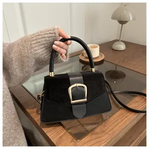 Close-up of black suede and smooth leather stitching with gold square buckle detail