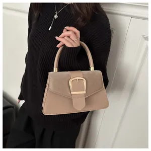 Detail of beige shoulder bag showing material texture and gold metal buckle close-up