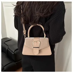 Detailed view of beige patchwork shoulder bag with gold buckle on model back