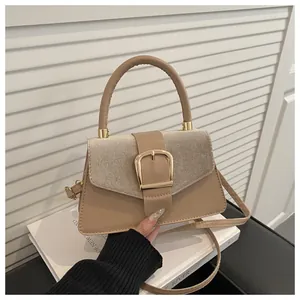 Detail of beige structured handbag featuring a large gold square buckle and textured flap