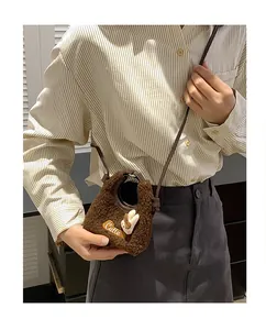 Detail of a brown fuzzy sherpa crossbody bag with Cutie embroidery and a bunny charm