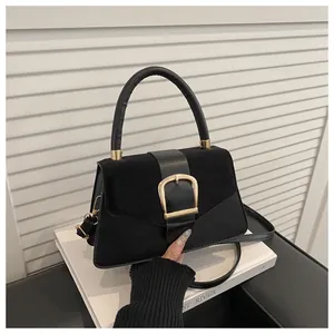 Detail of black suede and smooth leather stitching bag with large gold square buckle