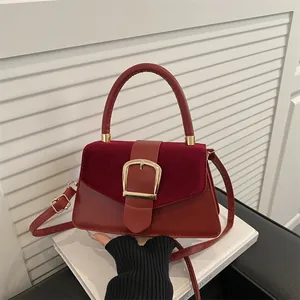 Deep red leather and suede shoulder bag featuring a gold horseshoe buckle and top handle