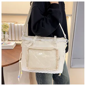 Detail of beige tote bag with white lace trim and a large transparent PVC front window