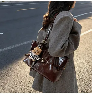 Détail du sac cabas en cuir ciré marron foncé avec boucle métallique et ours en peluche