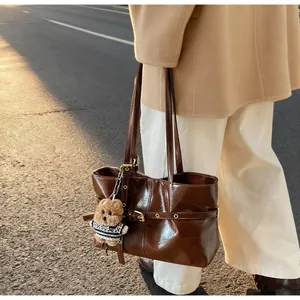 Détail d'un sac cabas en cuir ciré marron avec boucle latérale et breloque ourson