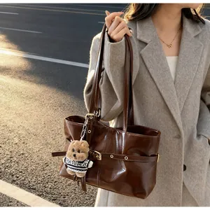 Sac cabas en cuir ciré marron avec breloque d'ours en peluche sous la lumière chaude