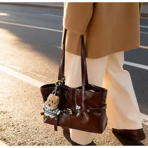 Détail du sac cabas en cuir ciré marron foncé avec matériel doré et breloque chien