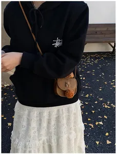 Dettaglio mini borsa a tracolla marrone con rilievo a forma di orso e pompon decorativo