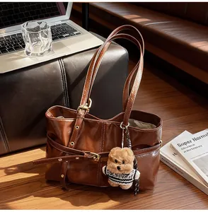 Détail du sac cabas en cuir ciré marron foncé avec boucle dorée et breloque ourson