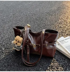 Détail du cabas en cuir ciré marron foncé avec un charm chiot et une bandoulière réglable