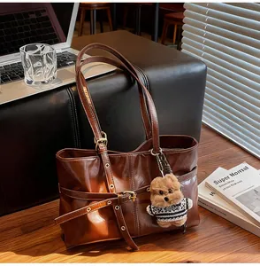Détail du cabas en cuir ciré avec boucle décorative et charm d'ours mignon