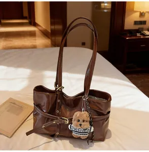 Détail d'un sac cabas en cuir ciré marron avec boucle dorée et petit pendentif en peluche