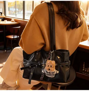 Détail du sac cabas en simili cuir noir avec œillets métalliques et pendentif chien peluche