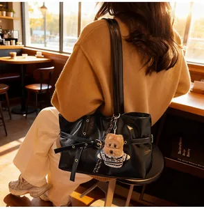 Détail d'un sac cabas en cuir noir brillant avec un pendentif chien rayé mignon