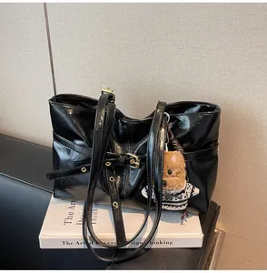 Détail d'un grand cabas noir brillant avec boucles en métal et breloque chien en peluche
