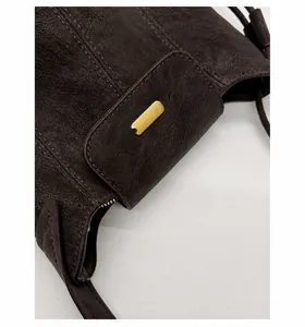 Close-up of vintage dark brown leather bag showing matte gold metal hardware and stitching