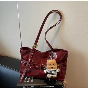 Détail du cabas en cuir ciré rouge foncé avec boucle décorative et breloque ours mignon