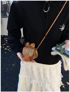 Dettaglio della borsa a tracolla marrone in peluche con fiocco e ornamento orso 3D